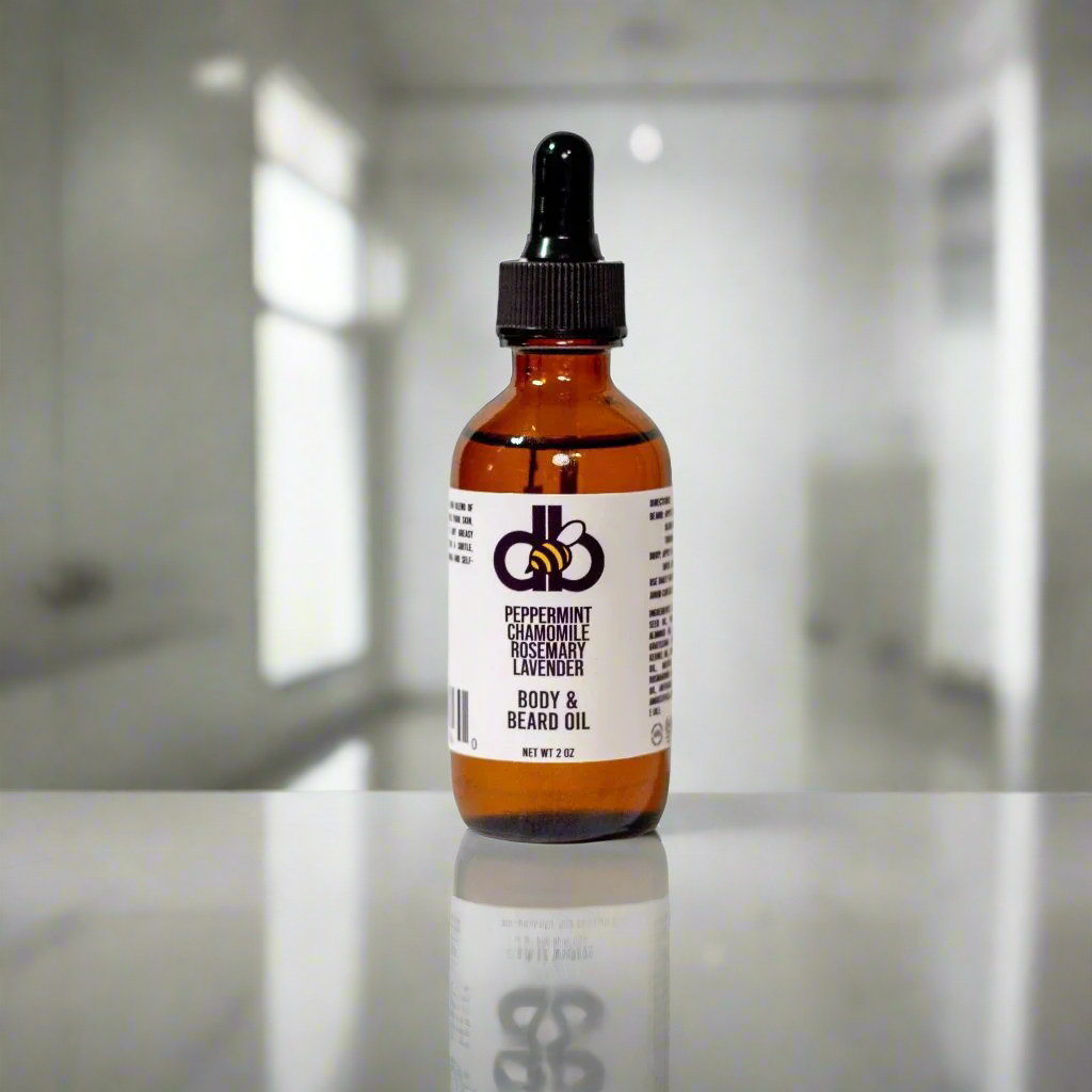 A brown glass dropper bottle labeled "Beard Taming Oil," from Diaz Beez, infused with essential oils such as peppermint, rosemary, chamomile, and lavender. Made from natural ingredients, it is placed on a reflective surface against a blurred white background that suggests a tranquil bathroom setting.