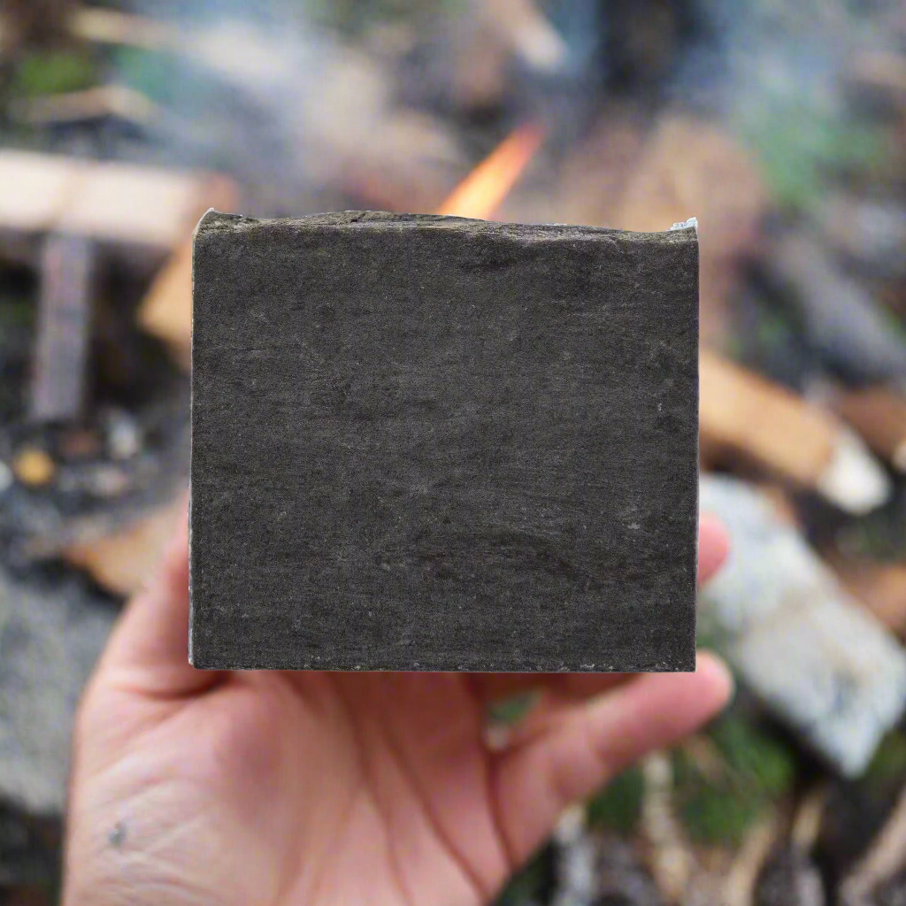 Hand holding "Into The Woods" soap bar with a natural background, highlighting the earthy, woodsy aroma.