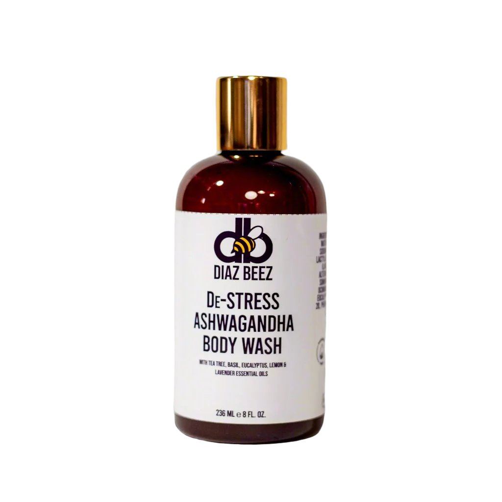 A brown plastic bottle with a gold cap, labeled "De-Stress Ashwagandha Body Wash" by Diaz Beez. The label features information on ingredients and volume, emphasizing essential oils of lime, basil, eucalyptus, lemon, and lavender for their stress-relief benefits. Bottle volume is 236 mL (8 fl. oz.).