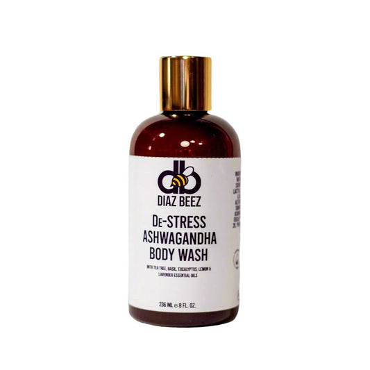 A brown plastic bottle with a gold cap, labeled "De-Stress Ashwagandha Body Wash" by Diaz Beez. The label features information on ingredients and volume, emphasizing essential oils of lime, basil, eucalyptus, lemon, and lavender for their stress-relief benefits. Bottle volume is 236 mL (8 fl. oz.).